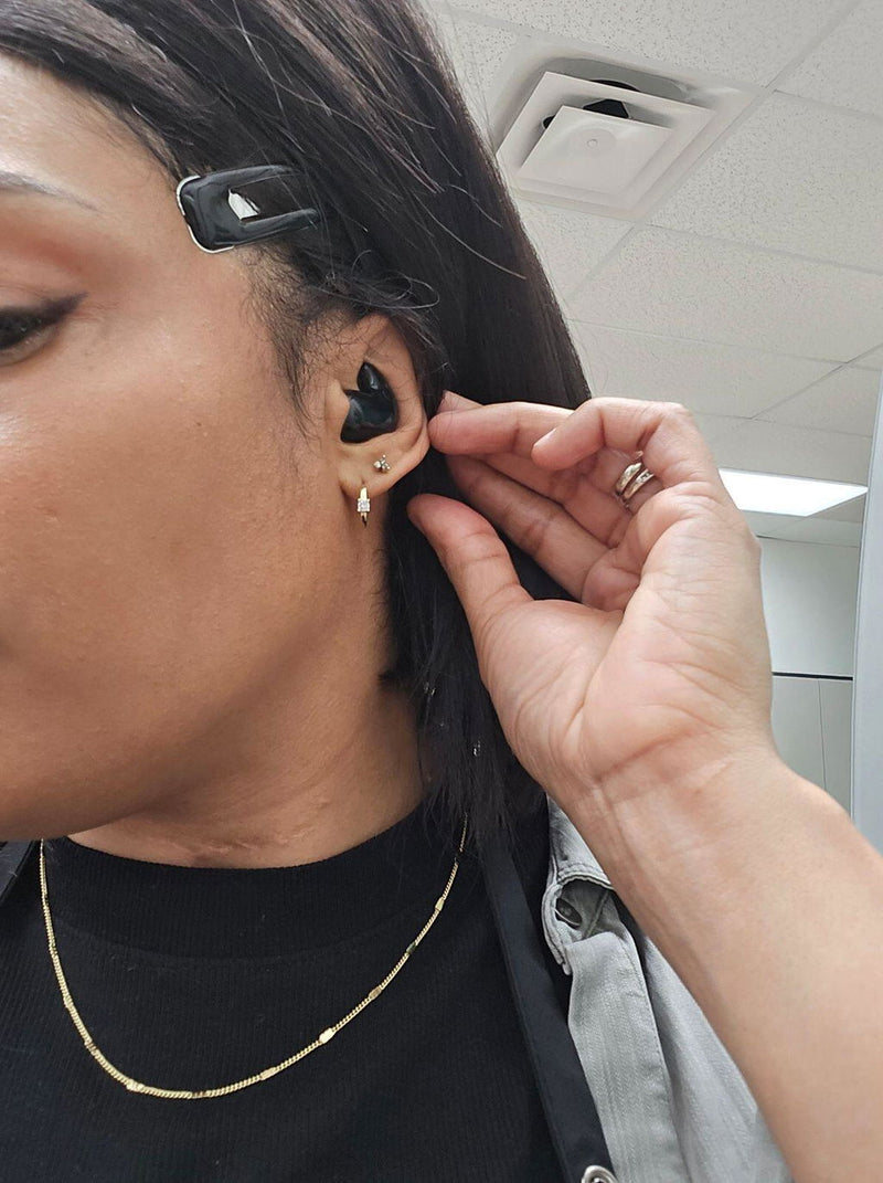 Customer putting a black ViSound Drift earbud in her ear